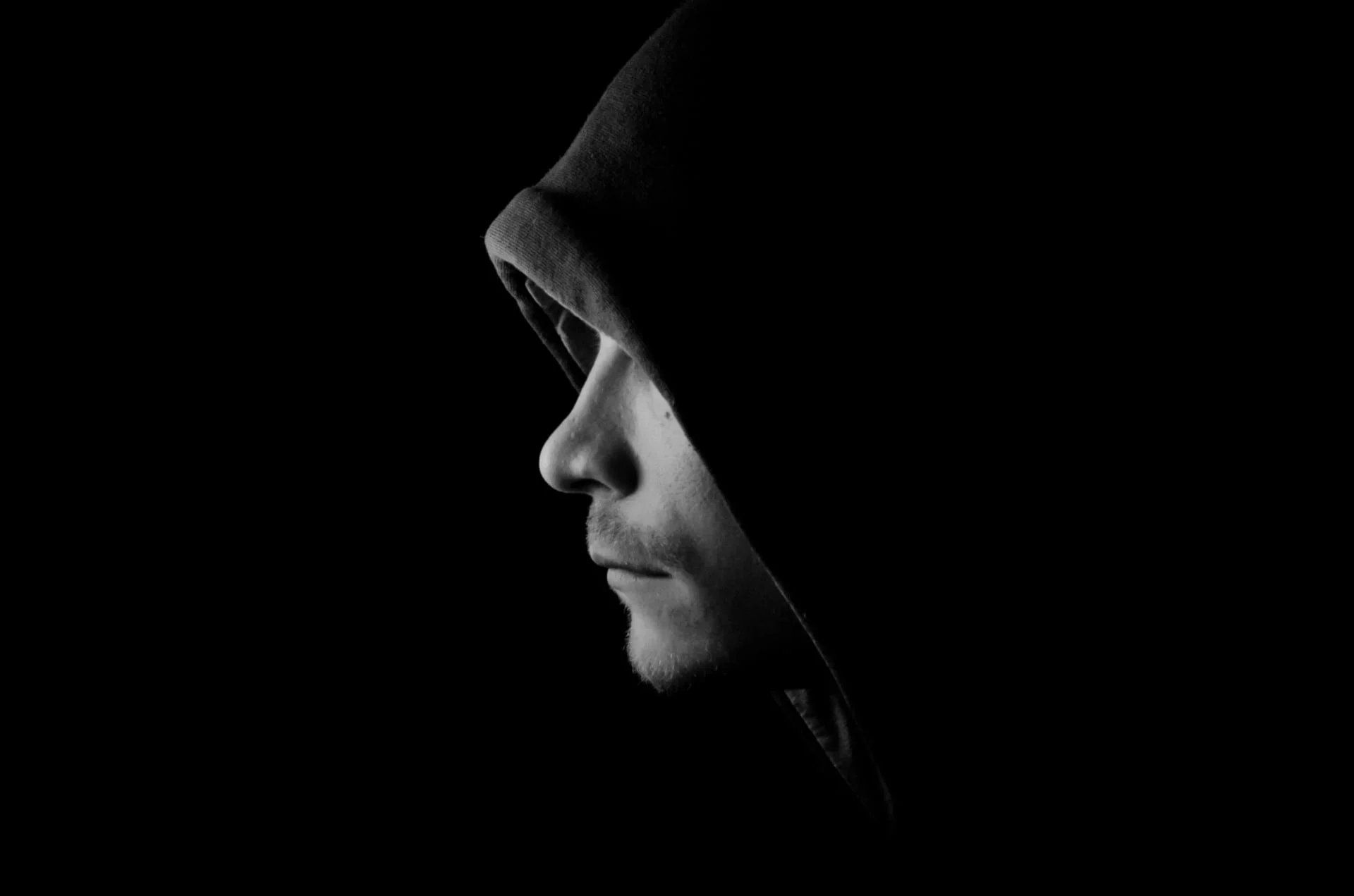 Hình nền đen ngầu chân dung người đàn ông mặc áo hoodie trong bóng tối